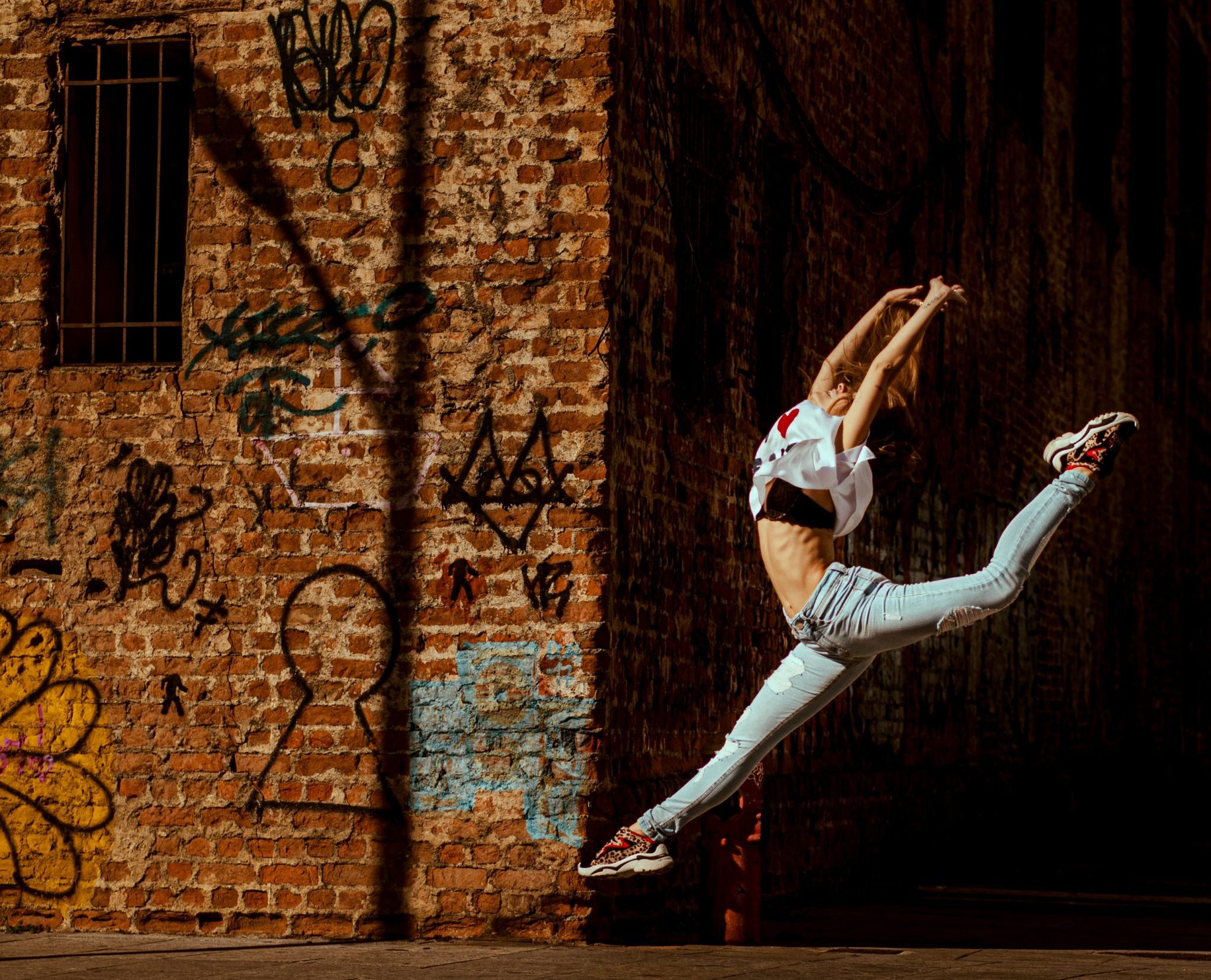 woman-jumping-near-brick-building-2895095